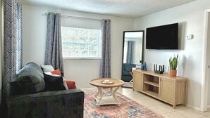 En stue med sofa, sofabord, fjernsyn og skab.