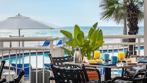 A balcony with a table set for breakfast, overlooking a pool and the ocean. - The Shores | Sunset Double | Beachside pool, yoga, resort vibes (Daytona Beach)