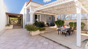 A covered patio area with a dining table and chairs, a pergola, and a small garden with plants. - Villa Miglietta by BarbaHouse (Torre Lapillo)