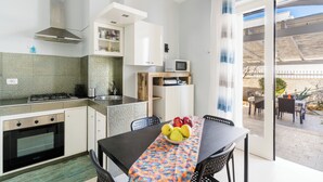 A modern kitchen with a dining area, a microwave, and a view of the outdoor patio. - Villa Miglietta by BarbaHouse (Torre Lapillo)