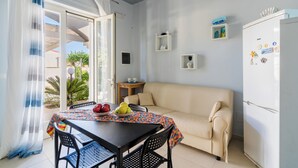 A compact living space with a dining table, a sofa, a refrigerator, and a small side table. - Villa Miglietta by BarbaHouse (Torre Lapillo)