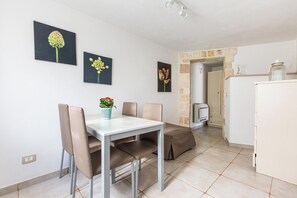 A dining area with a table, chairs, and a potted plant. There are framed pictures on the wall.