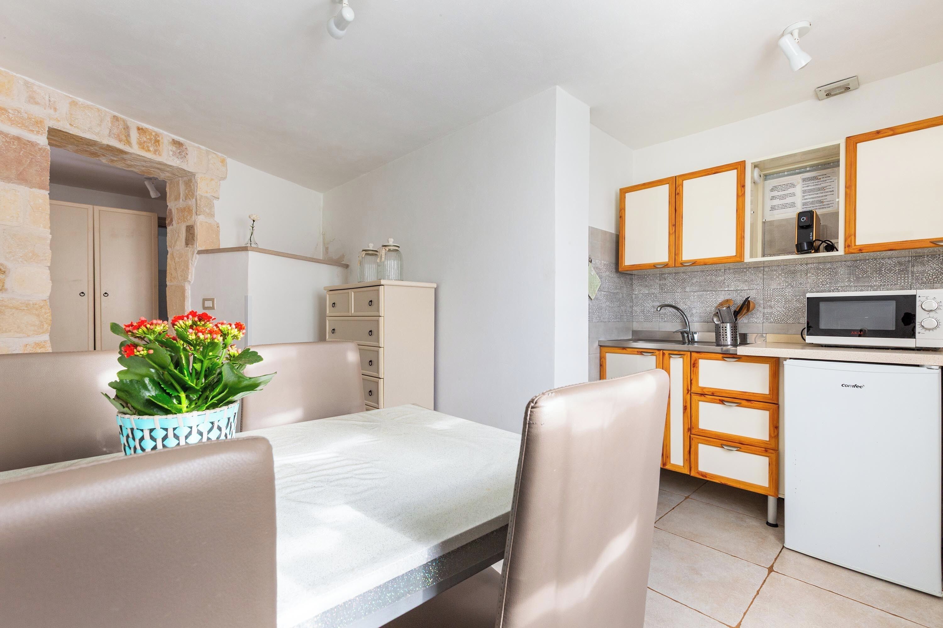 Eine kleine Küche mit Mikrowelle, Kühlschrank und Holzschränken.