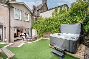 A modern house with a hot tub, artificial grass, and a patio area. - Rosemount Boutique (Windermere)