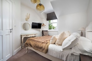 A bedroom with a bed, a dresser, a TV, and a window. - Rosemount Boutique (Windermere)