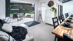 Ett modernt kök med matplats, en vägg av natursten och utsikt över den utomhusbelägna terrassen.