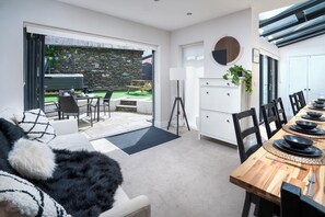 A modern kitchen with a dining area, stone wall, and a view of the outdoor patio. - Rosemount Boutique (Windermere)