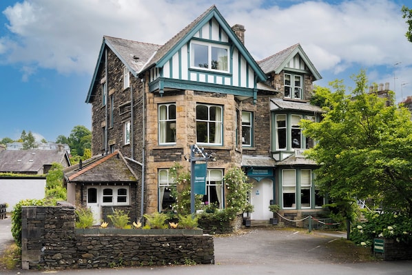 A stone building with a green and white facade, multiple windows, and a sign indicating it is a hotel. - Rosemount Boutique (Windermere)