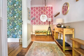 Ein Zimmer mit Holzboden, einer Bank, einem Schreibtisch mit Lampe und einer Wand mit Blumenpapier.