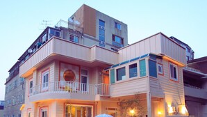 A multi-story residential building with balconies, a covered porch, and a brick wall. - SoSi Stay (Seoul)