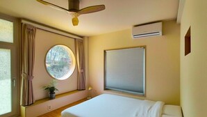 A bedroom with a bed, a ceiling fan, a window with curtains, a potted plant, and an air conditioning unit. - SoSi Stay (Seoul)