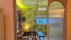A room with a wooden dining table, chairs, a potted plant, and a sliding glass door leading to another room. - SoSi Stay (Seoul)