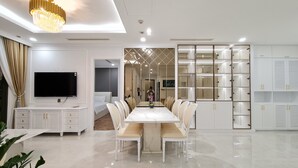 Una habitación de hotel moderna con una amplia mesa de comedor, un televisor y un armario con espejo.