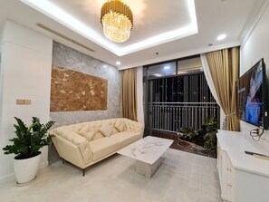 Ein modernes Wohnzimmer mit einer Couch, einem Marmortisch, einer Zimmerpflanze, einem Fernseher und einem großen Fenster mit Vorhängen.