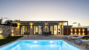 Ett modernt hus med en swimmingpool, en uteplats och en mur av sten.