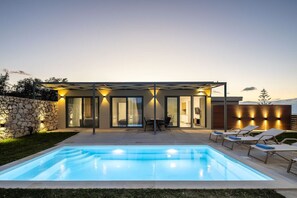 A modern house with a swimming pool, outdoor seating, and a stone wall. - Stylish Villa w/ Heated Pool & BBQ, near Rethymno (Rethymnon)