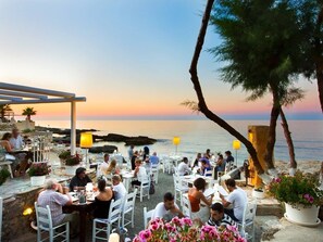 An outdoor dining area with tables and chairs, overlooking a body of water. - Stylish Villa w/ Heated Pool & BBQ, near Rethymno (Rethymnon)