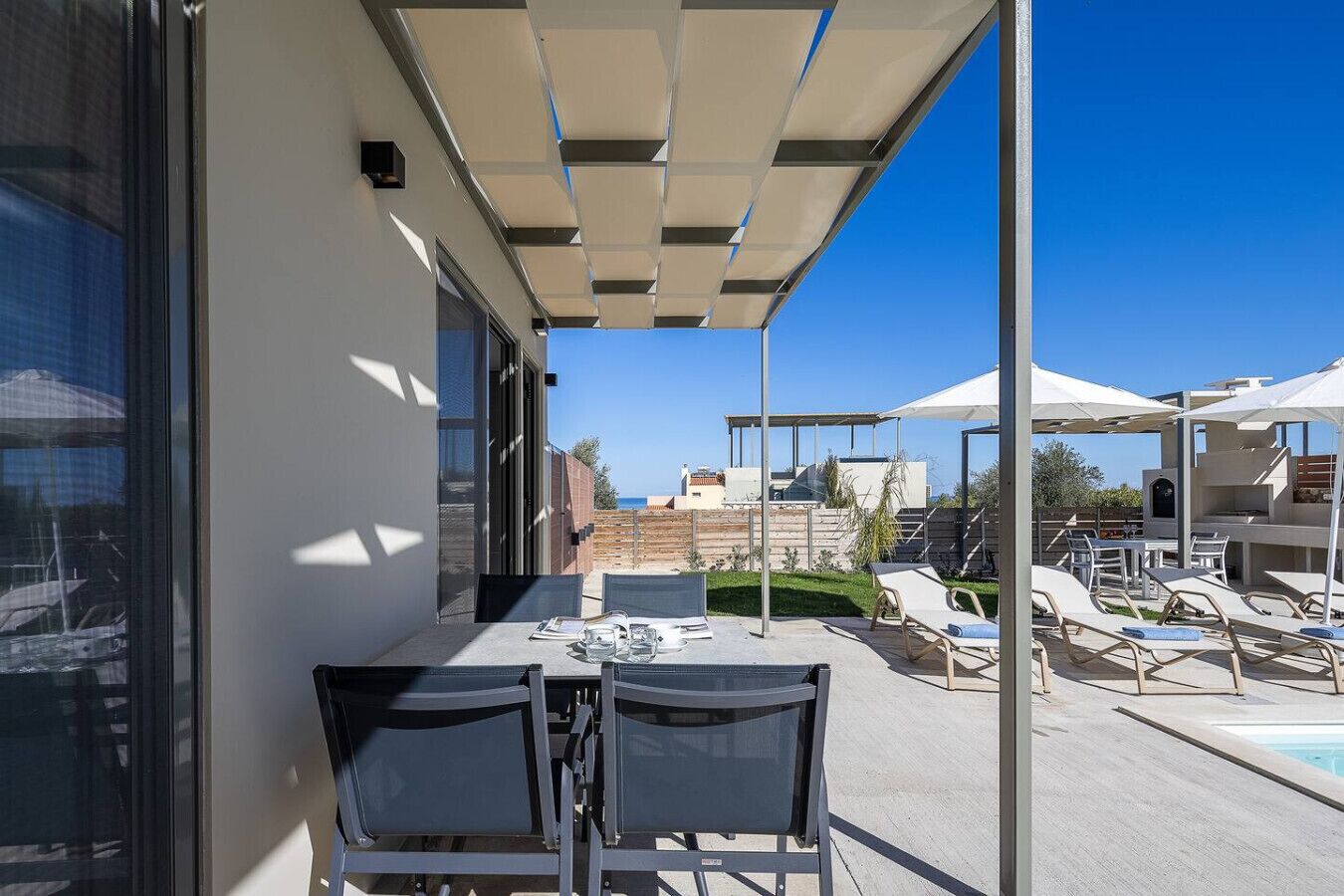 Patio moderno all'aperto con piscina, sedie a sdraio e zona pranzo.