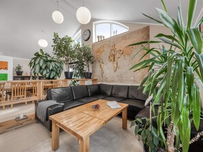A modern living room with a black leather sofa, wooden coffee table, and multiple potted plants. - 4 Star Holiday Home in Lokken (Lokken)