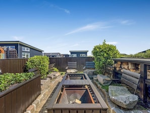 A backyard with a wooden deck, a fire pit, and a wooden fence. - 4 Star Holiday Home in Lokken (Lokken)