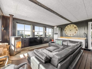 A modern living room with a large leather sofa, a fireplace, and a clock on the wall. - 4 Star Holiday Home in Lokken (Lokken)