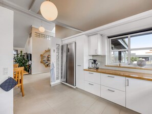 A modern kitchen with white cabinetry, a stainless steel refrigerator, and a coffee machine. - 4 Star Holiday Home in Lokken (Lokken)