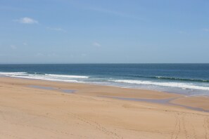Ein Strand mit breitem Sandufer und sanften Wellen.