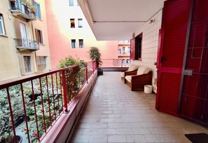 A narrow balcony with a red railing, a pair of wooden chairs, and a red door. - BIG Fiera Terrace (Amendola - Duomo M1) (Milan)