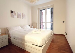 A bedroom with a bed, a nightstand, a radiator, and a window with a view. - BIG Fiera Terrace (Amendola - Duomo M1) (Milan)
