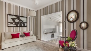 Een woonkamer met een bank, een stoel, een salontafel en een keuken op de achtergrond.