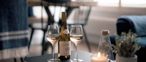 Una botella de vino y dos copas sobre una mesa con una vela y una planta en maceta.