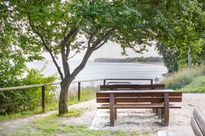 A bench under a tree by a body of water. - Apartment 'Dünenhaus Südstrand' with Pool Access in Prime Location (Göhren)