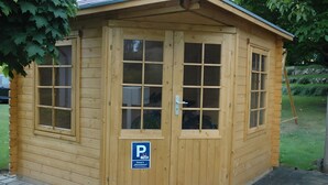 Un bâtiment en bois doté de nombreuses fenêtres et d’une porte, avec un panneau indiquant un espace de stationnement.