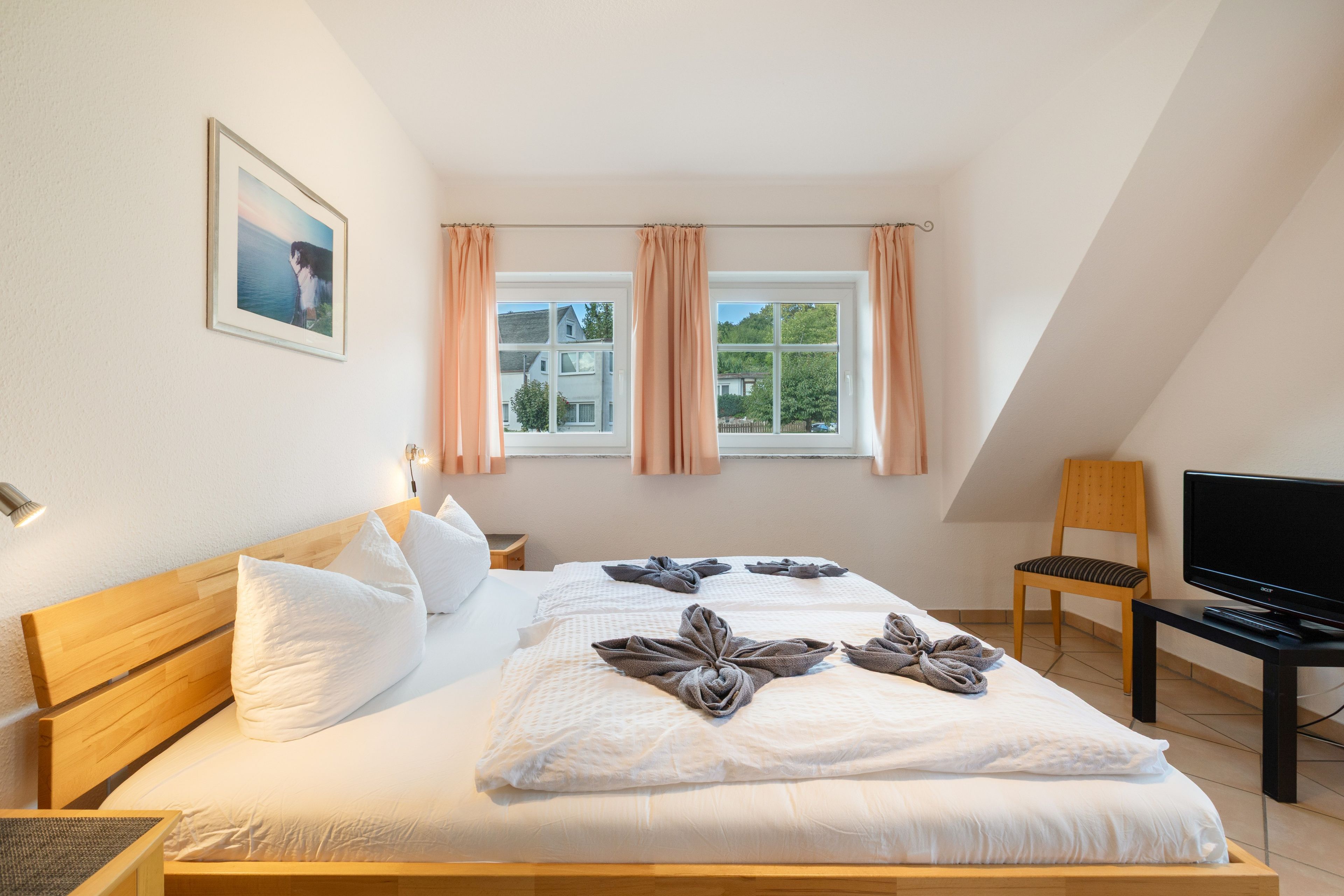 Een hotelkamer met een bed, een televisie, een stoel en een raam met gordijnen.