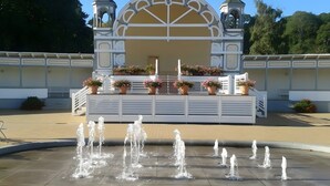Une fontaine dotée de plusieurs jets d’eau se trouve devant un bâtiment à la façade blanche et agrémentée d’éléments décoratifs.