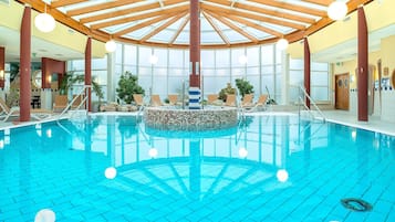 Ein Innenpool mit Fliesenboden, Holzbalken und einem zentralen Mosaikbild.