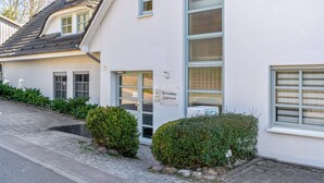 A building with a sign reading 'Ferienhaus Sudstrand,' a paved entrance, and a small hedge. - Apartment 'Fewo Südstrand Schwimmbadnutzung' with Sea View, Sauna and Wi-Fi (Göhren)
