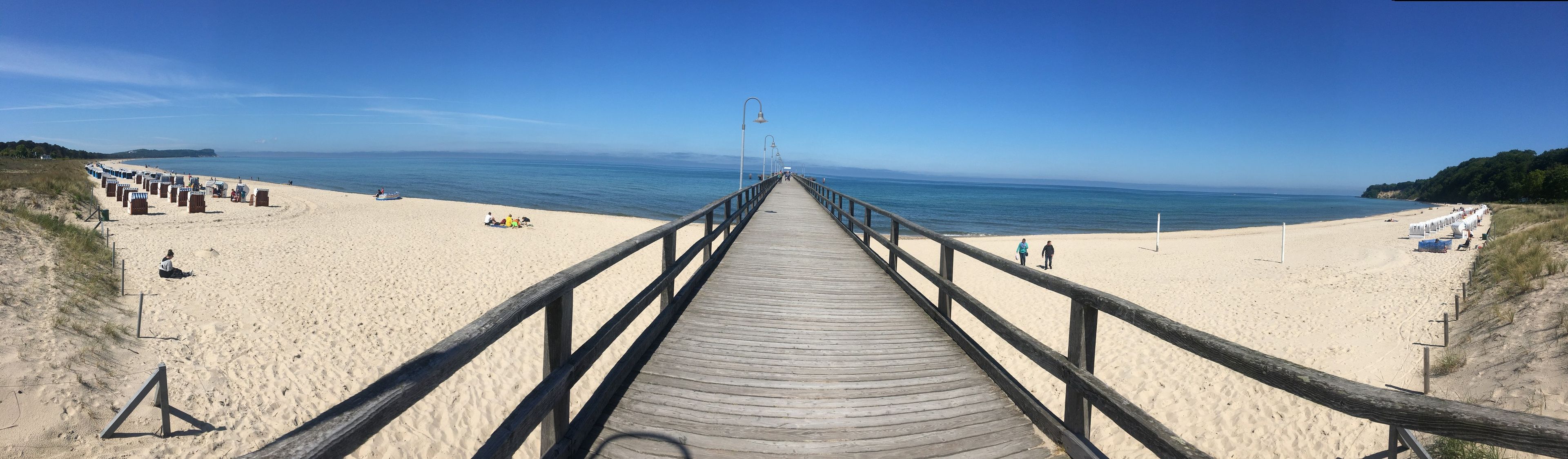 Une promenade en bois mène à une plage de sable, d’où l’on a une vue dégagée sur l’océan.