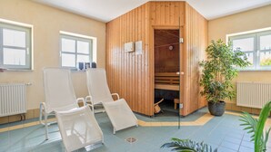 A sauna room with wooden walls, a bench, and a potted plant. - Apartment 'Fewo Südstrand Schwimmbadnutzung' with Sea View, Sauna and Wi-Fi (Göhren)