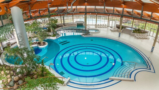 An indoor swimming pool with multiple lanes, a diving board, and a seating area with chairs. - Apartment 'Fewo Südstrand Schwimmbadnutzung' with Sea View, Sauna and Wi-Fi (Göhren)