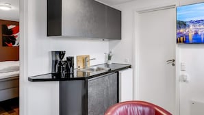 Eine kleine Küche mit schwarzem Arbeitsplatz, einer Kaffeemaschine, einem Messerblock und einem kleinen Spülbecken.