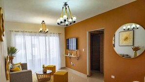 Una sala de estar moderna con sofá, reposapiés y televisor.
