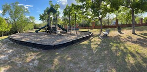 A playground with a slide, climbing structures, and a bench.