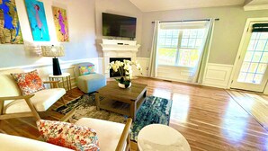 A living room with a fireplace, a television, and a large window.