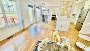 A spacious room with hardwood flooring, a dining area with a table and chairs, and a kitchen with white cabinetry.