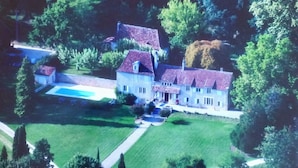 Vista aérea de una extensa propiedad con varias construcciones, una piscina y céspedes bien cuidados.