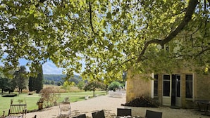 Un patio al aire libre con una mesa y sillas, rodeado de árboles y vistas al campo.