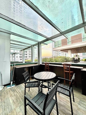 Un espace extérieur moderne, aménagé avec un toit de verre, du mobilier en bois et offrant une vue sur le paysage urbain.