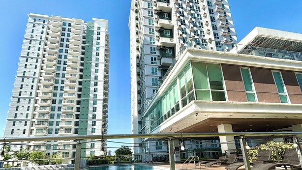 Un edificio alto con piscina y sillones de descanso.