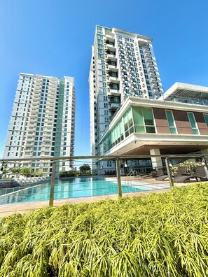 Um edifício alto com piscina e espreguiçadeiras.
